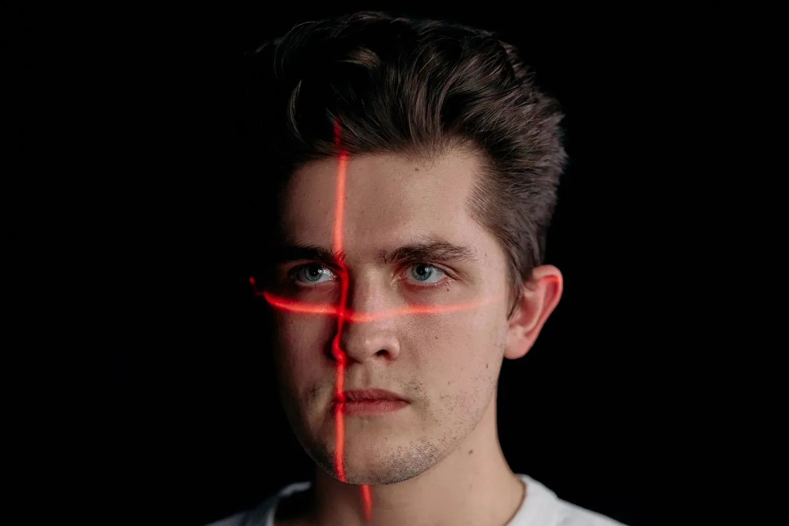 Rostro escaneado por un haz de luz que representa la manipulación facial con inteligencia artificial en un deepfake | Sanahuja Abogados Penalistas